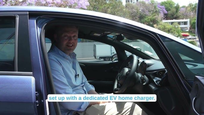 En mand sidder i førersædet af en elbil og taler om hjemmeopladning. En mand sidder i førersædet af en elbil og taler om hjemmeopladning.