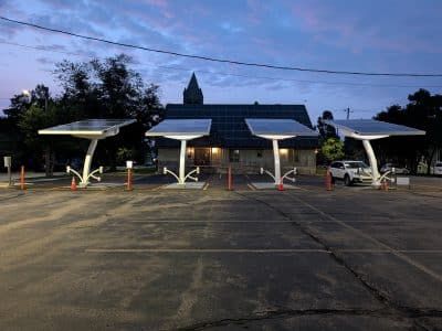 Moderne solcelledrevne ladestationer til elbiler på en parkeringsplads ved aftenstide.